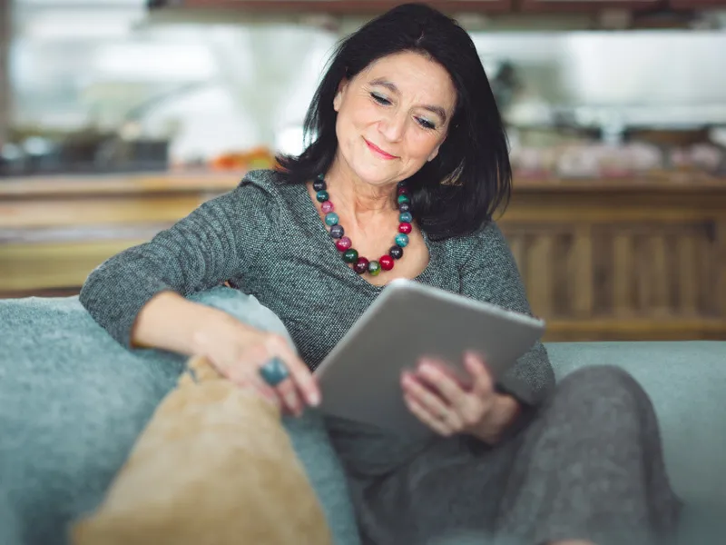 woman seating reading her tablet and smiling